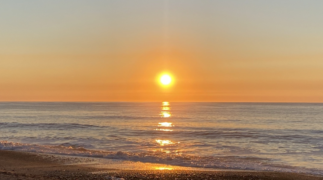 Sunrise from the beach reflecting on the waves
