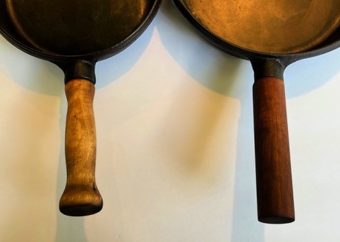 two cast iron pans with wooden handles