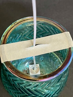 Jar with tape on it to hold the candle wick for homemade candles