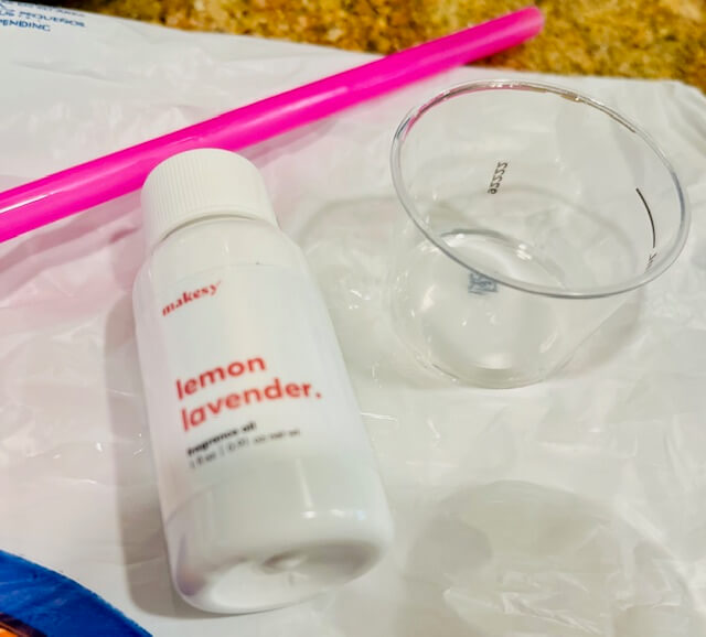 fragrance oil, measuring cup and straw