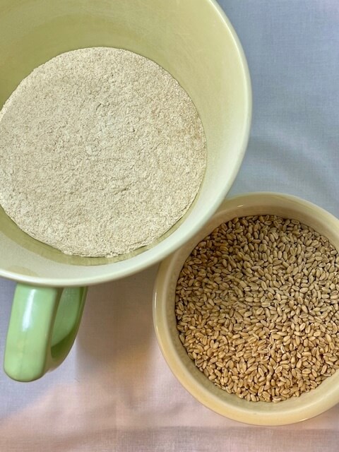 Bowl of flour and bowl of wheat berries for berry wheat bread