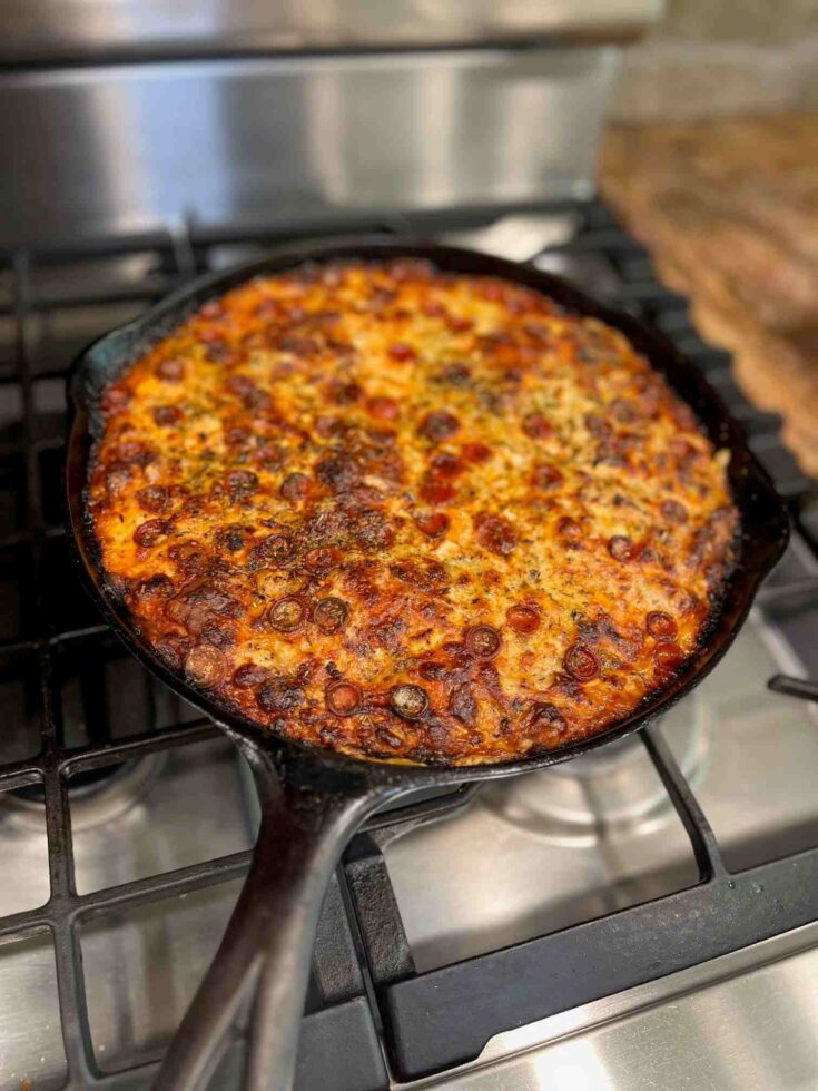 Fresh Milled flour Pizza crust in a cast iron with cheese and pepperoni sitting on a stovetop