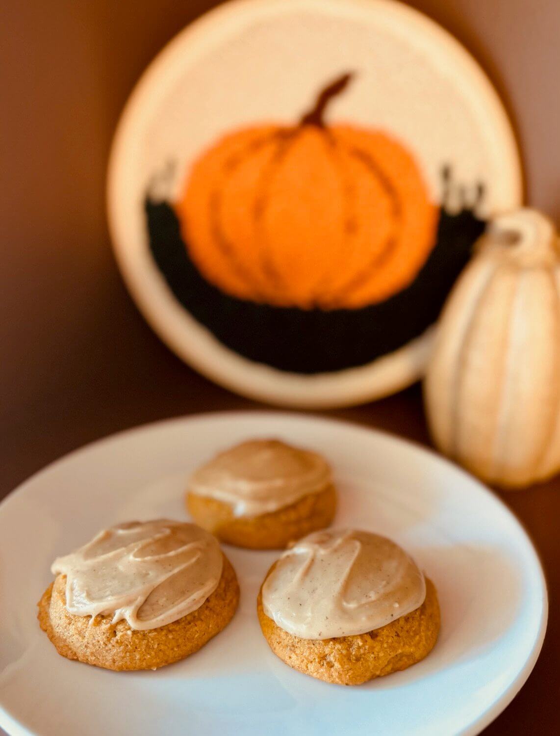 Three Pumpkin Cookies freshly milled flour on a white plate with a pumpkin in the background.