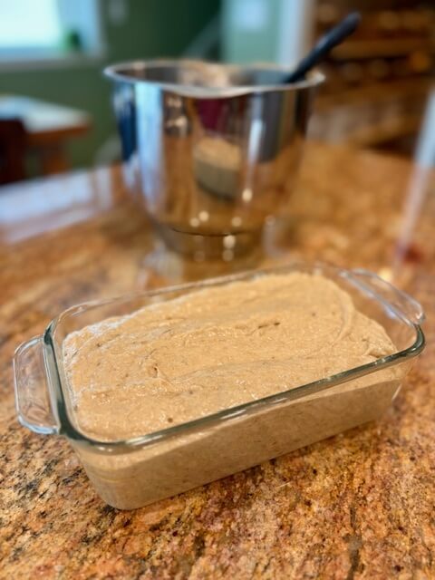 fresh milled flour banana bread batter in a greased glass pan on a counter