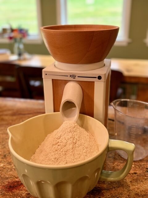 grain mill with bowl full of freshly ground flour