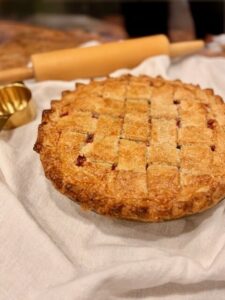 fresh milled flour pie crust with cherry filling on a counter with a rolling pin behind it