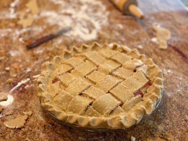 fresh milled flour pie crust that is in a pan with a woven top and cherry pie filling