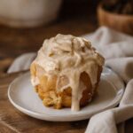 Sourdough Cinnamon Rolls on a white plate sitting on a wooden cutting board