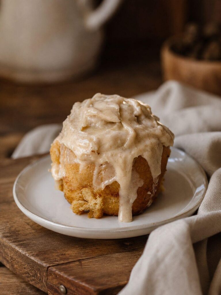 Sourdough Cinnamon Rolls on a white plate sitting on a wooden cutting board