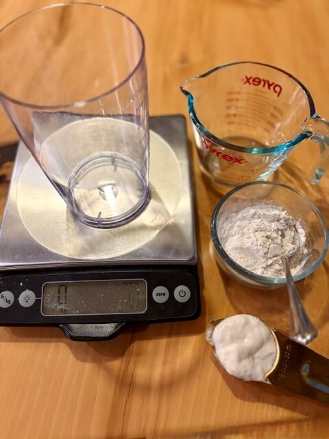 Kitchen Scale with water, flour and sourdough starter on a counter