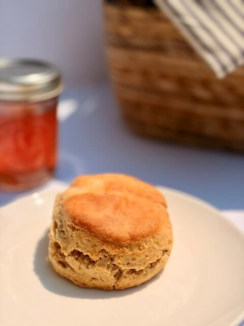 fresh milled flour biscuits on a white plate with jam in the background
