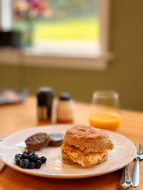 fresh milled flour biscuits on a white plate with other breakfast food