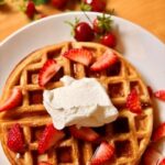 Fresh Milled Flour Waffles with strawberries and whipped cream on a white plate