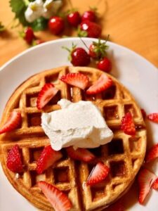 Fresh Milled Flour Waffles with strawberries and whipped cream on a white plate
