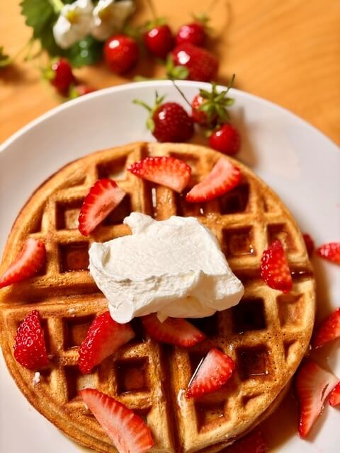 Fresh Milled Flour Waffles with strawberries and whipped cream on a white plate