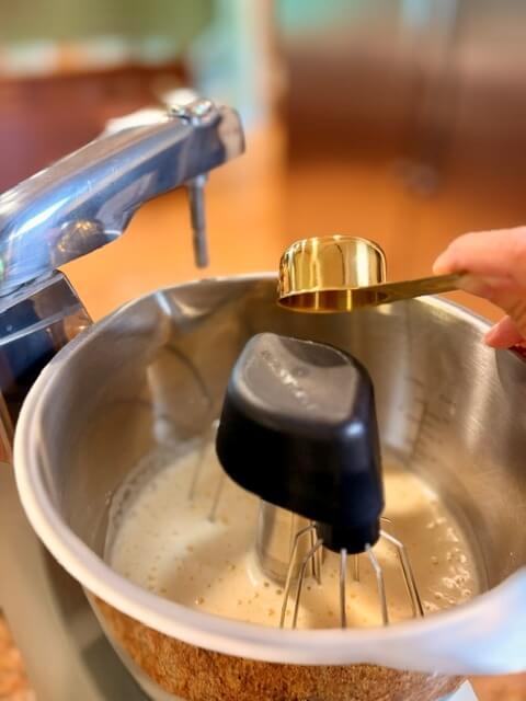 Sugar being added to mixed eggs in mixing bowl