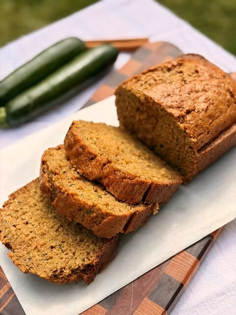 Fresh Milled Flour Zucchini Bread on a cutting board with zucchini and cinnamon stick in the background
