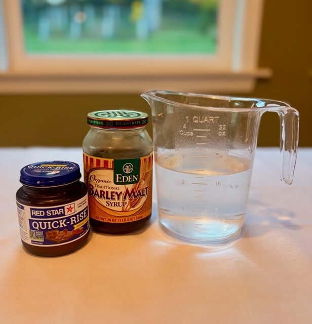 Yeast, water, and barley malt syrup on a countertop