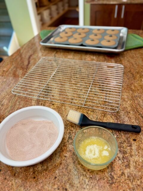 cinnamon sugar and butter in bowls next to wire rack and fresh milled flour apple cider donuts