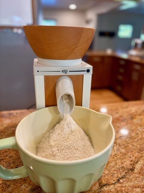 fresh milled flour being ground on a counter into a green bowl